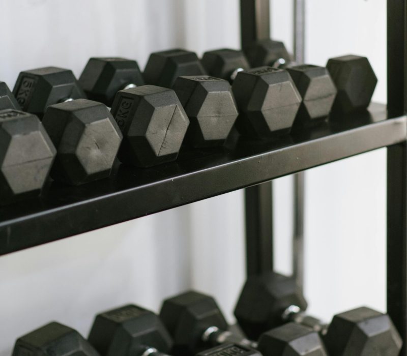 Organized hexagonal dumbbells stacked on a sturdy rack in a modern gym setting.