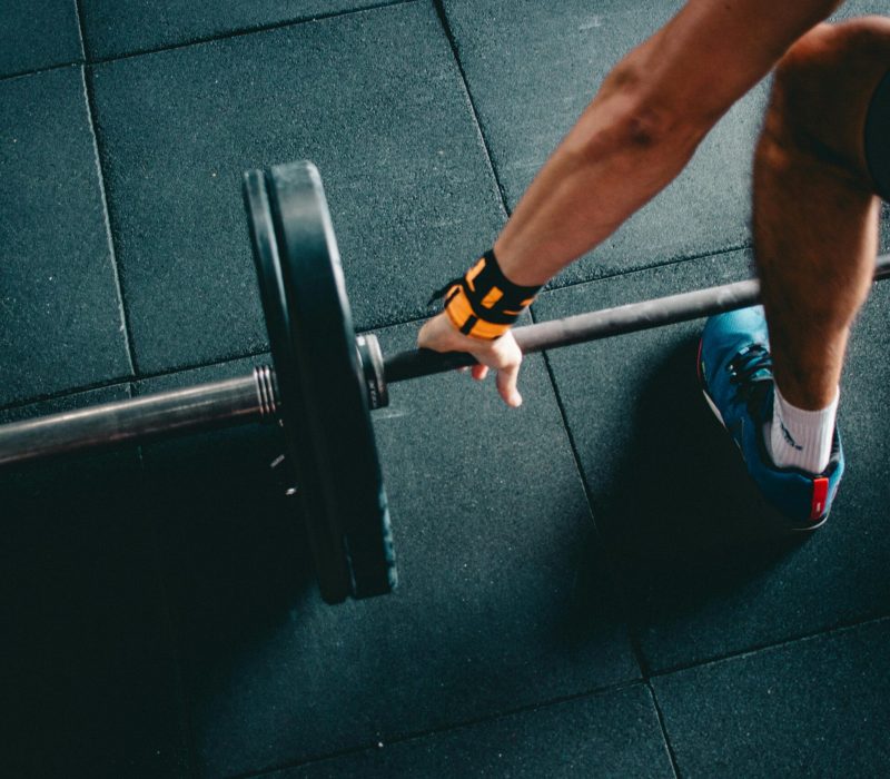 Close-up of a person lifting a barbell in an indoor gym, focusing on strength training.